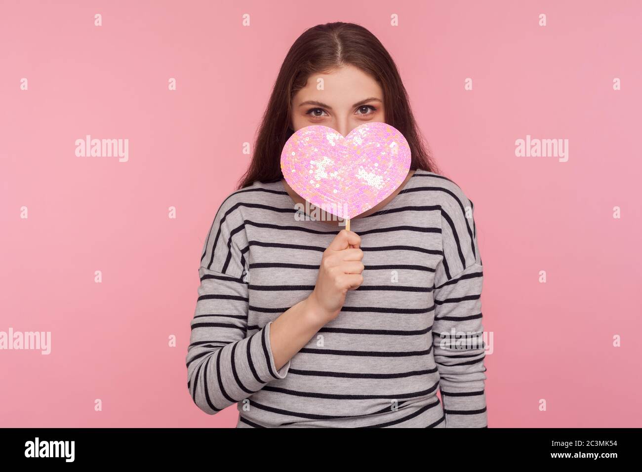 Sei mein Valentinstag! Portrait von kokettisch fröhliche Frau piepend aus glänzenden rosa Herz mit verspielten glücklichen Blick, demonstriert Liebe Pflege, romantisches Gefühl Stockfoto