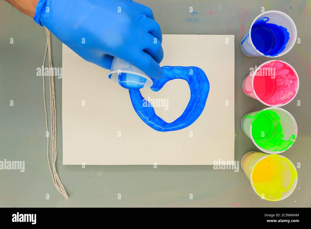 Hand Gießen blaue Acrylfarbe auf eine Künstler Leinwand Stockfoto