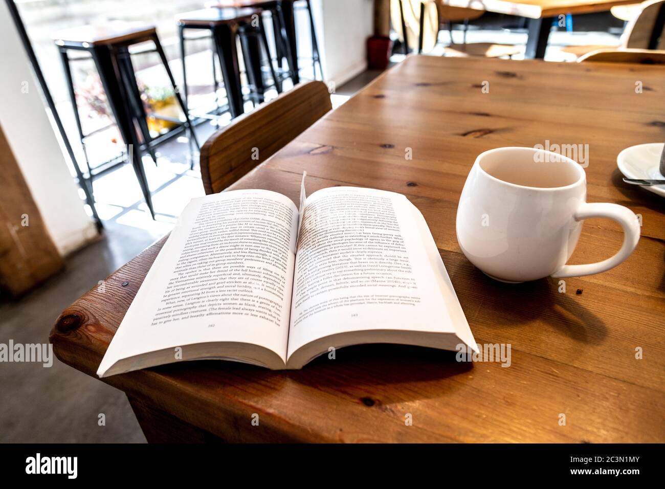 Buch und eine Tasse Tee auf einem Tisch in einem Café Stockfoto
