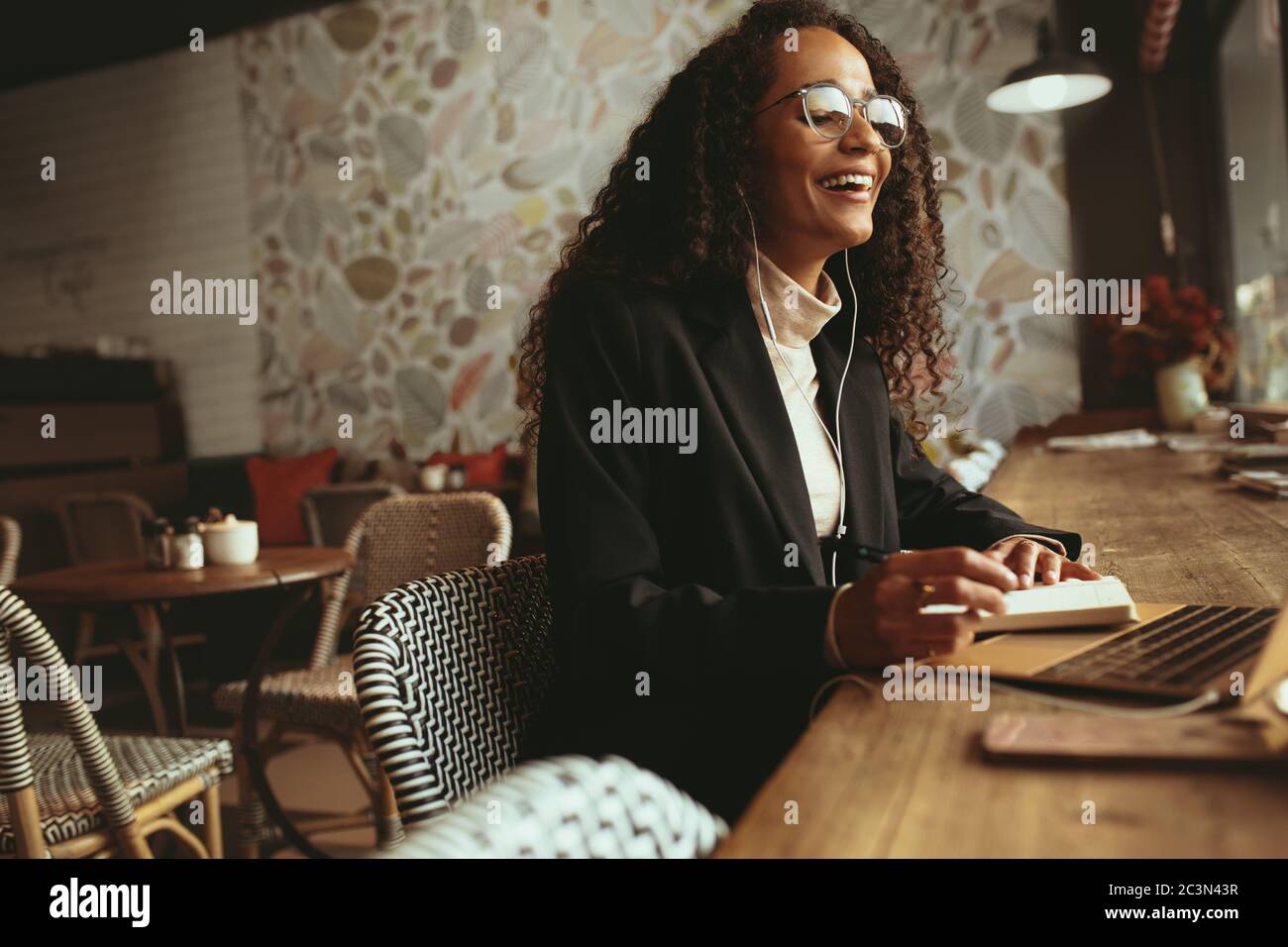 Lächelnde Frau, die im Café einen Videoanruf auf ihrem Laptop hat. Geschäftsprofi sitzt am Kaffeetisch und hat eine Videokonferenz. Stockfoto