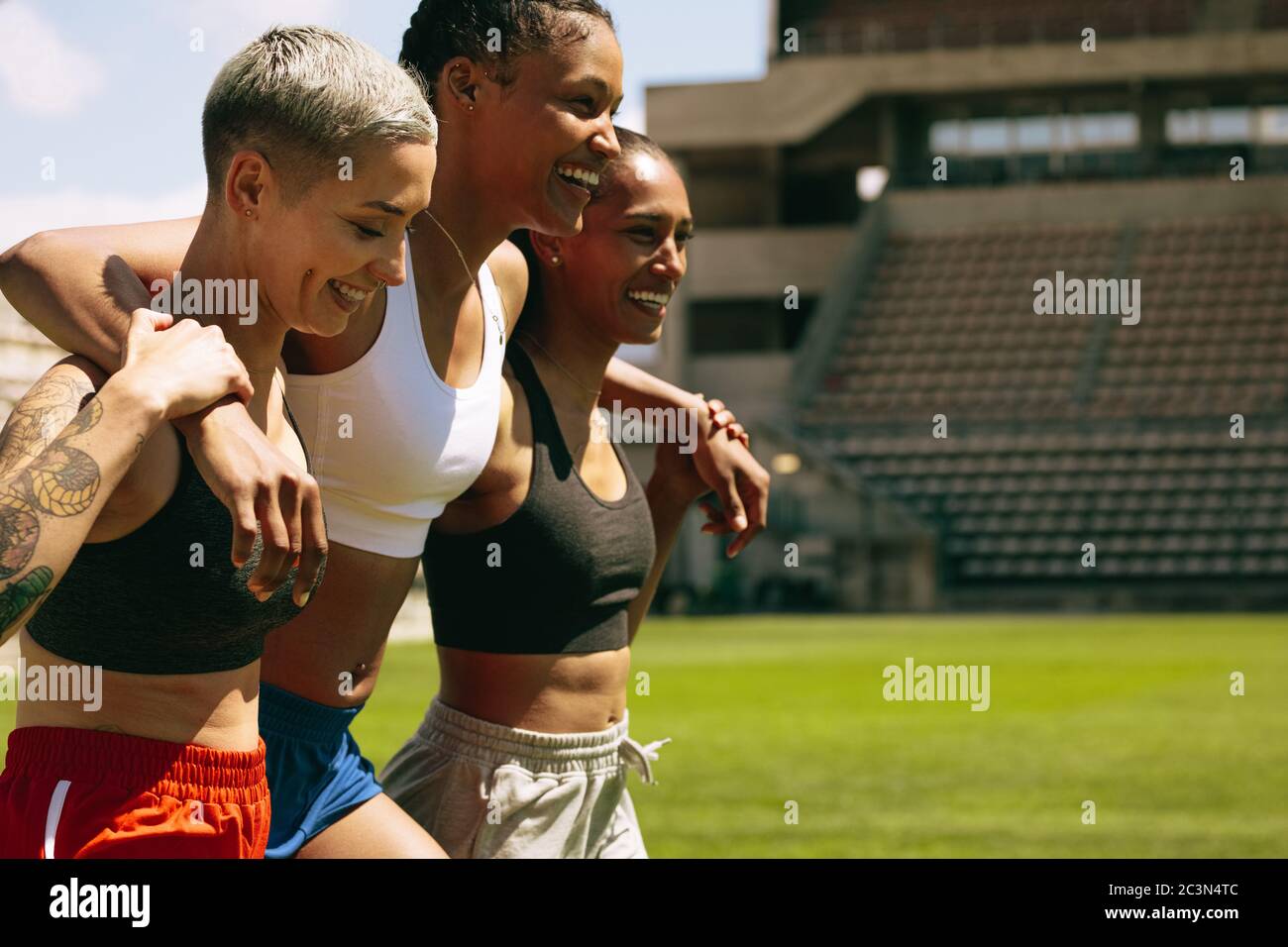 Gruppe von drei weiblichen Athleten, die nach dem Training gemeinsam auf dem Sportplatz spazieren. Multiethnische Sportlerin nach einem Training im stadi Stockfoto