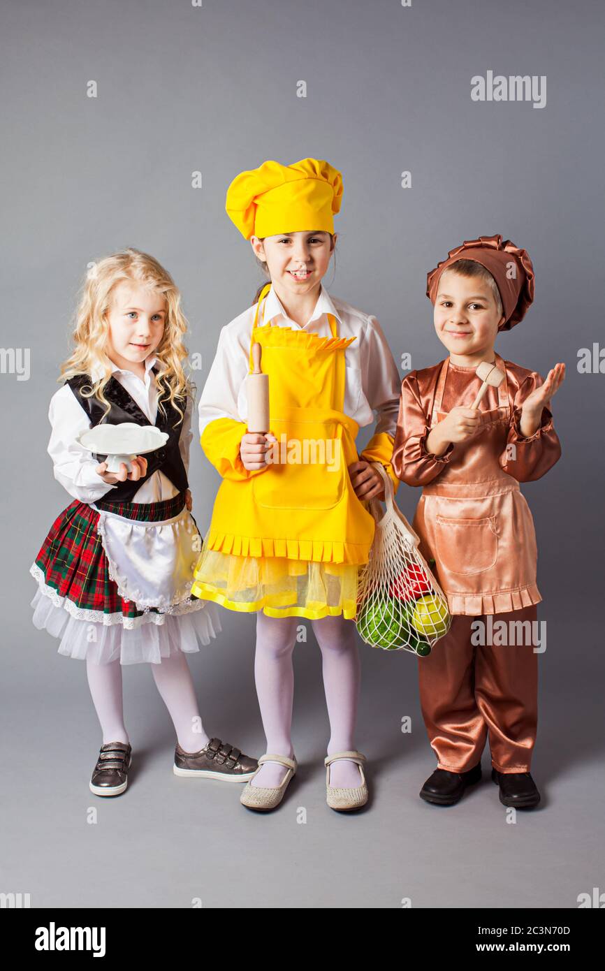 Gruppe von Kindern spielen in Zukunft Beruf. Kinder tragen Kostüme von Koch, Bäcker und Kellner. Stockfoto