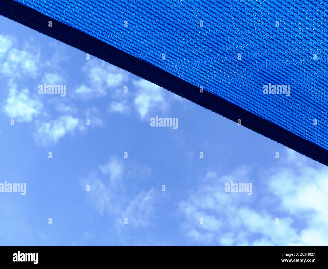 Sonnenschirm und Markise aus aufgehängtem Stoff. Blauer Himmel mit Wolken. Sonniger Sommertag. Sonnenschutz- und UV-Schutzkonzept. Blaues, sonnenfestes Stoffzelt Stockfoto