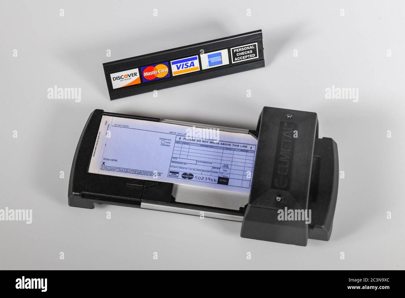 Manuelle Kreditkartenmaschine - alte Technik - ein manuell bedienter Kreditkartendrucker mit Kreditkartenlogos - persönliches Scheckschild Stockfoto
