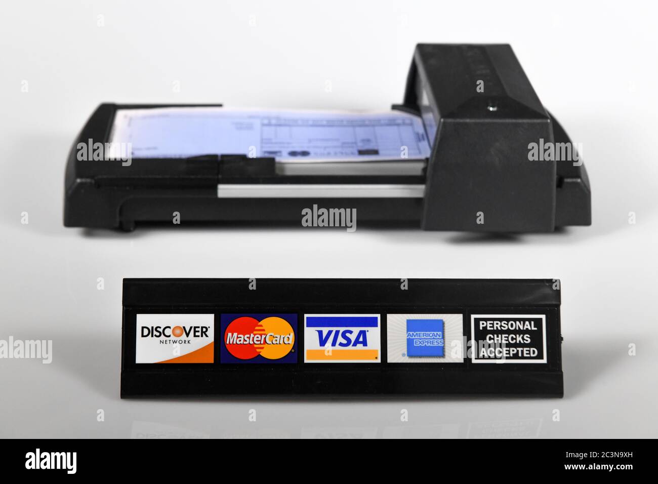 Manuelle Kreditkartenmaschine - alte Technik - ein manuell bedienter Kreditkartendrucker mit Kreditkartenlogos - persönliches Scheckschild Stockfoto
