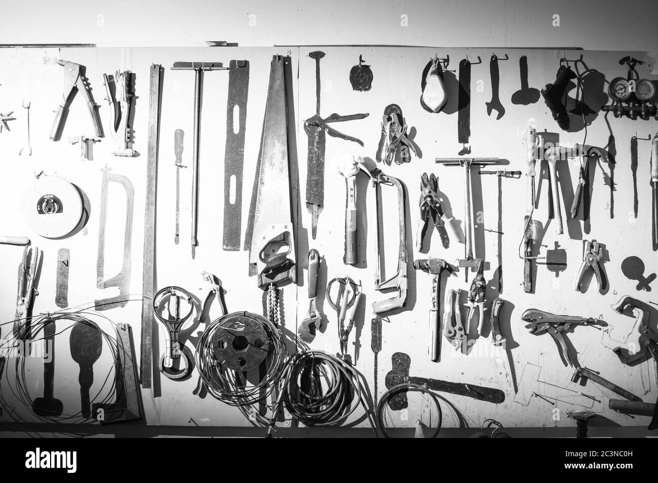 Alte Werkzeuge hängen an der Wand in der Werkstatt. Dunkle und Vintage-Ton-Tapete. Stockfoto
