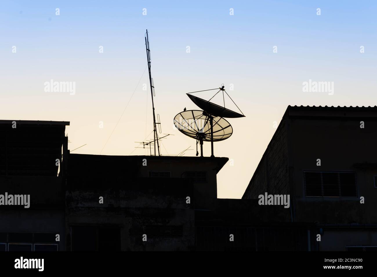 Silhouetten Satellitenschüsseln auf dem Dach vor Sonnenaufgang. Stockfoto