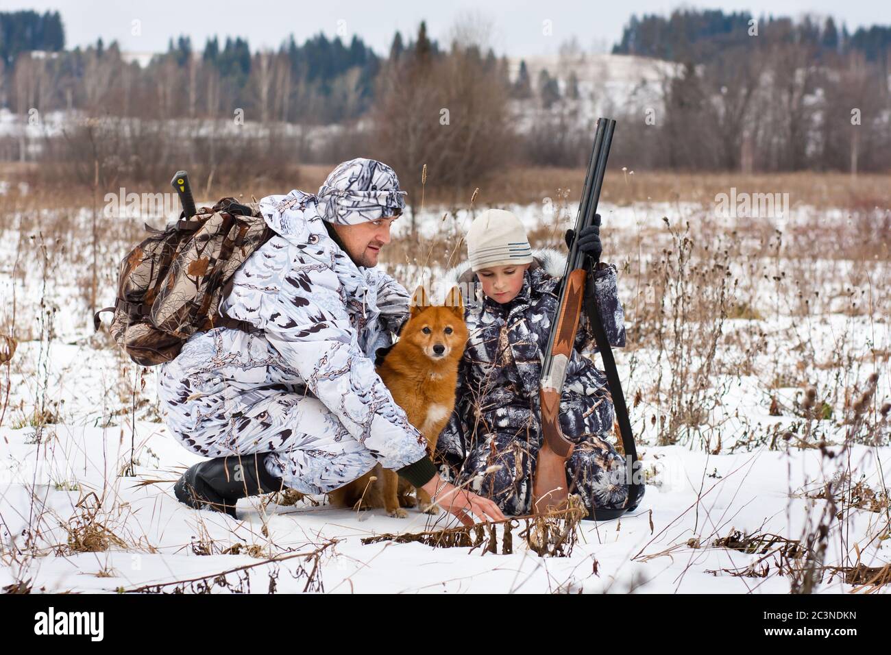 hunter zeigt seinem Sohn Spuren von Tieren auf der Winterjagd Stockfoto