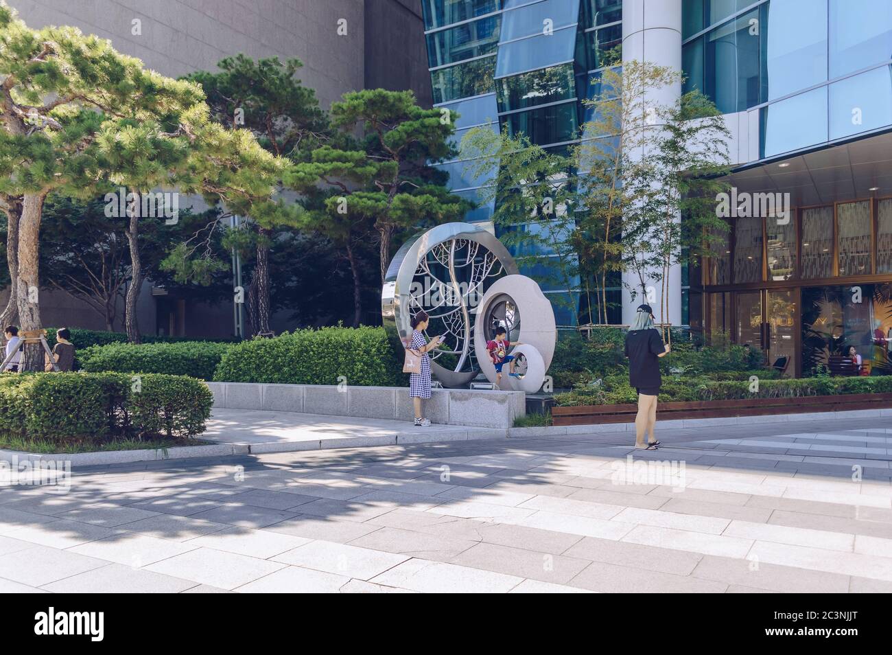 Busan, Südkorea 15. September 2019: Landschaftlich gestalteter Bereich in der Nähe eines großen Einkaufszentrums mit Bäumen und moderner Skulptur Stockfoto