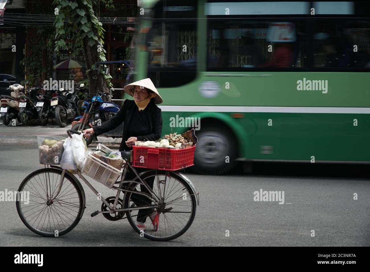 Eine alte vietnamesische Frau hält an und verkauft Straßenessen auf der belebten Straße. Ho Chi Minh Stadt, Vietnam, 17. März 2017. Stockfoto