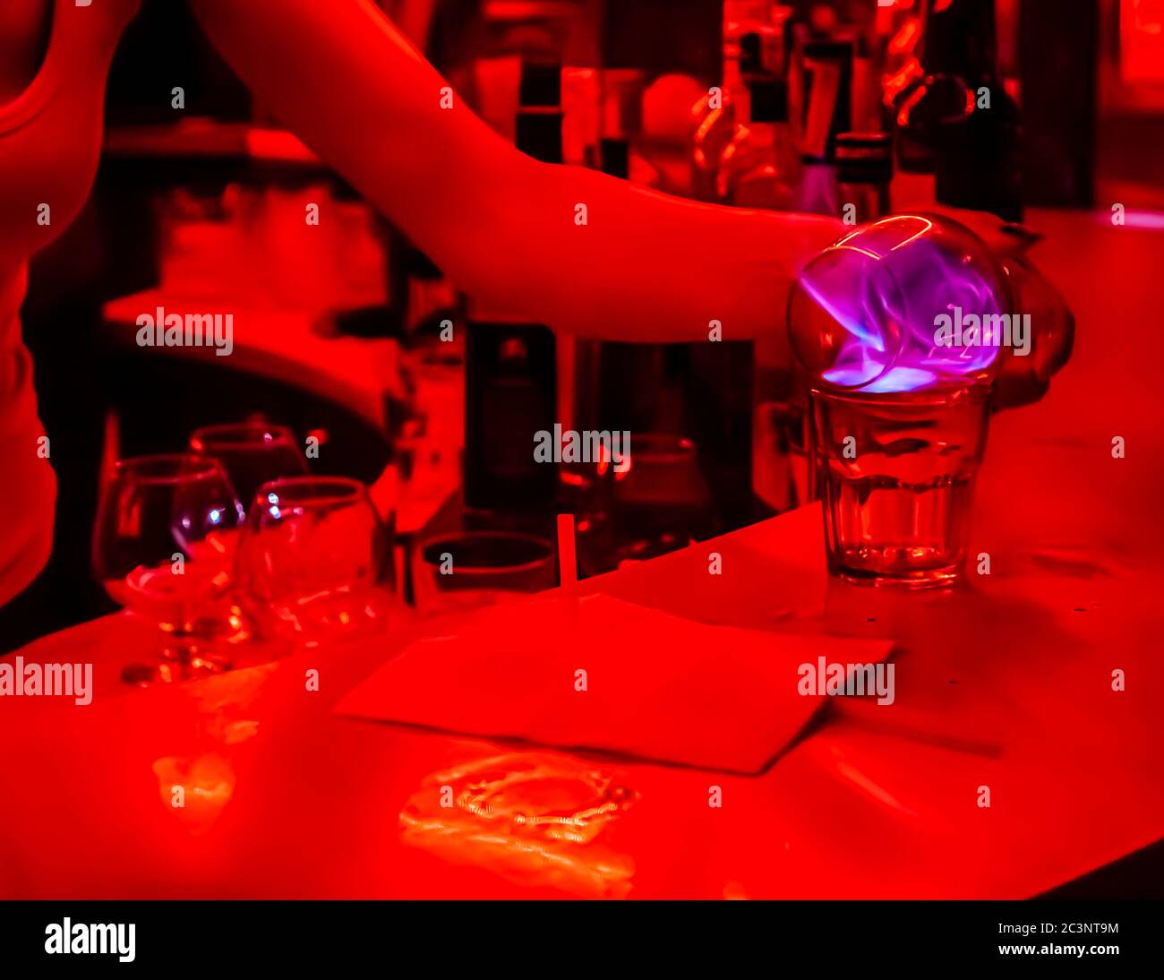 Rotlichtclub in Bulgarien. Wettbewerb, bei dem der verdunstende Alkohol von flambiertem Jägermeister mit einem Stroh eingeatmet wird Stockfoto