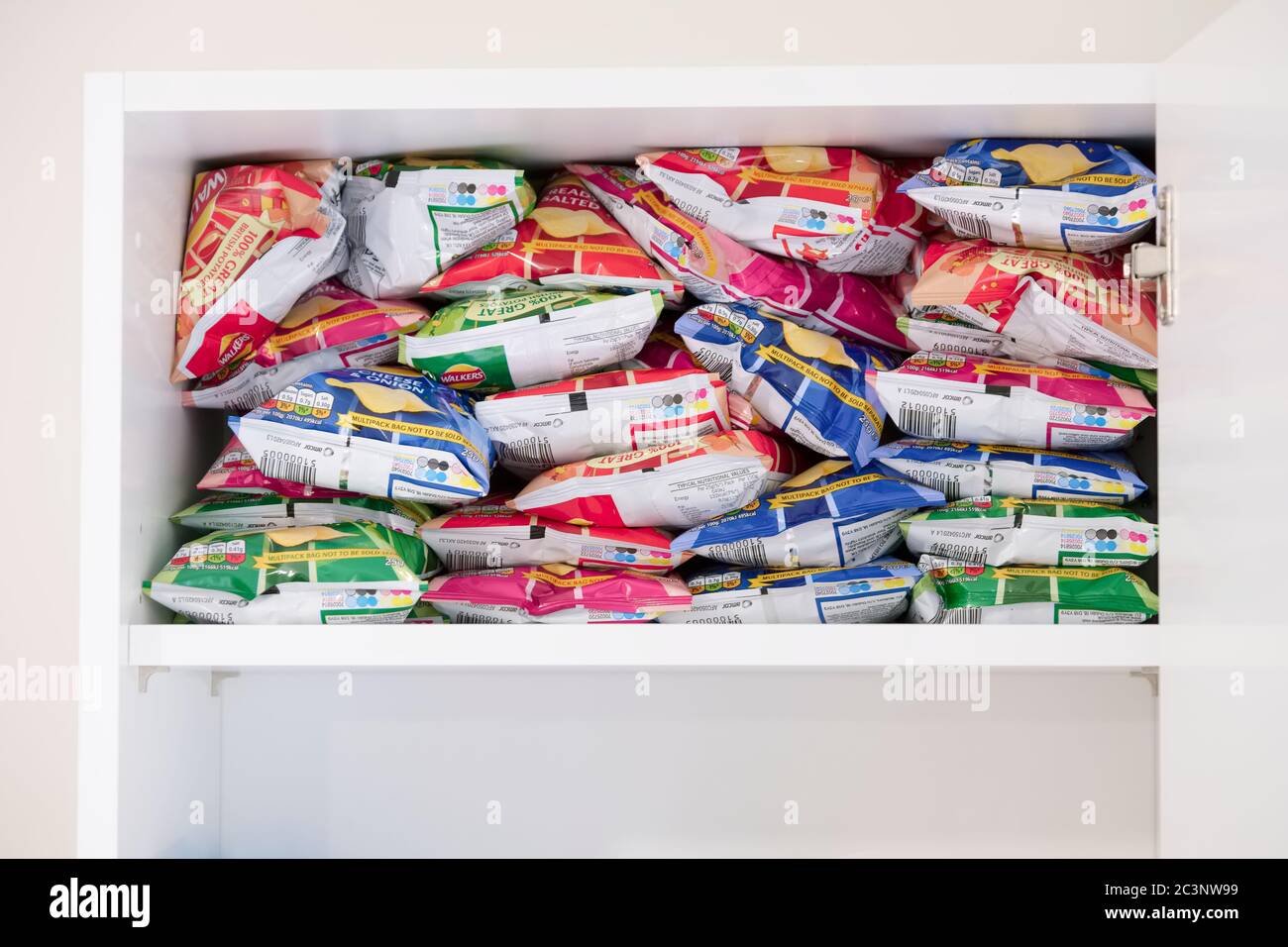 London, England / Großbritannien - 2. Juni 2020: Knackige Pakete im Küchenschrank gestapelt, da ungesunde Essgewohnheiten zunehmen Stockfoto