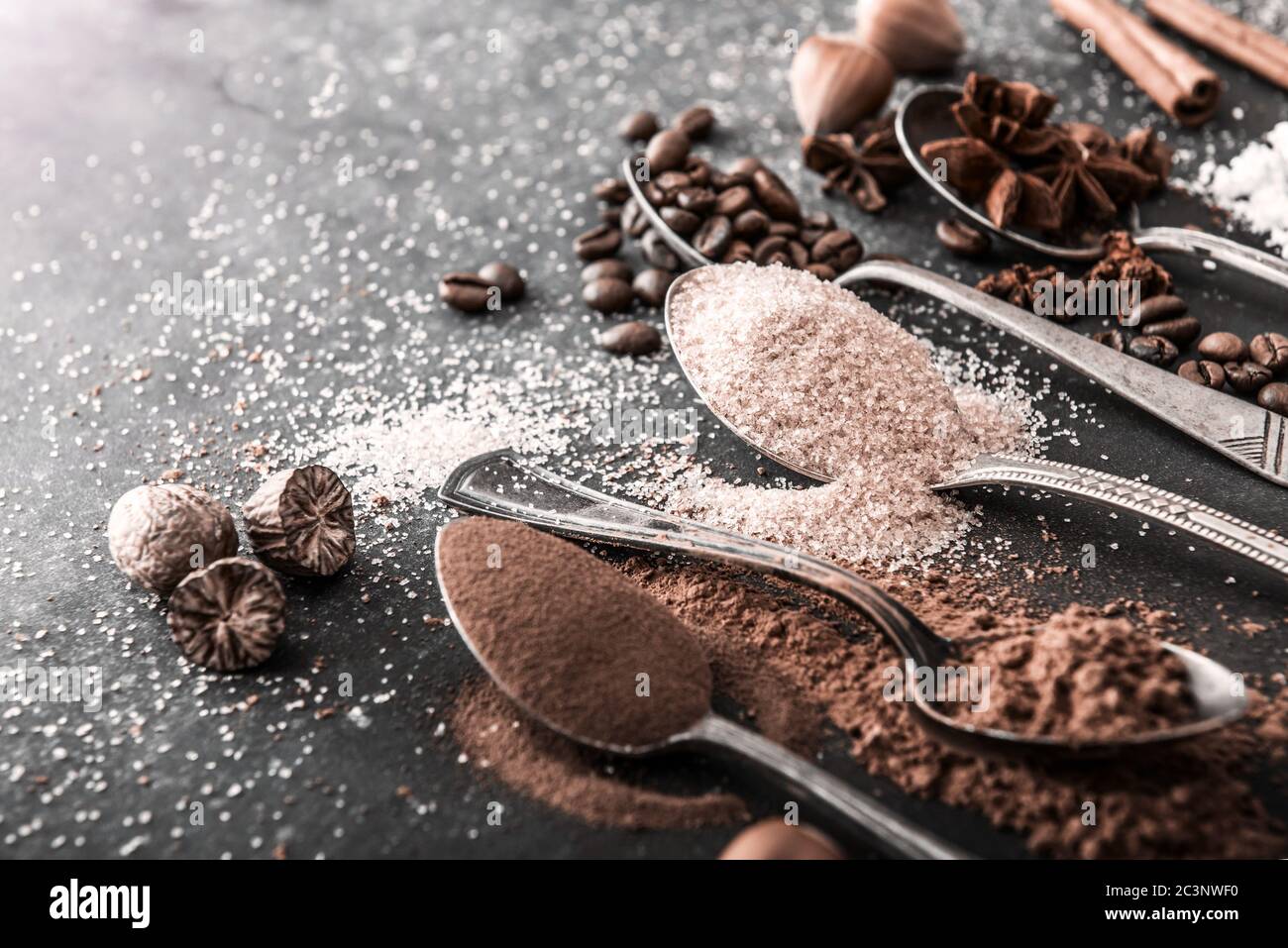 Schokoladenpulver Kakao und Kaffeelöffel auf dem Tisch schwarz Stockfoto
