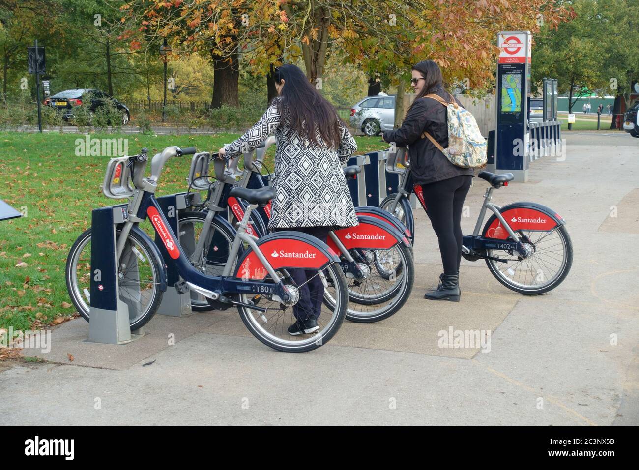 Zwei Frauen im Fahrradständer mit Santander Leihfahrrädern im Hyde Park, London, Großbritannien Stockfoto