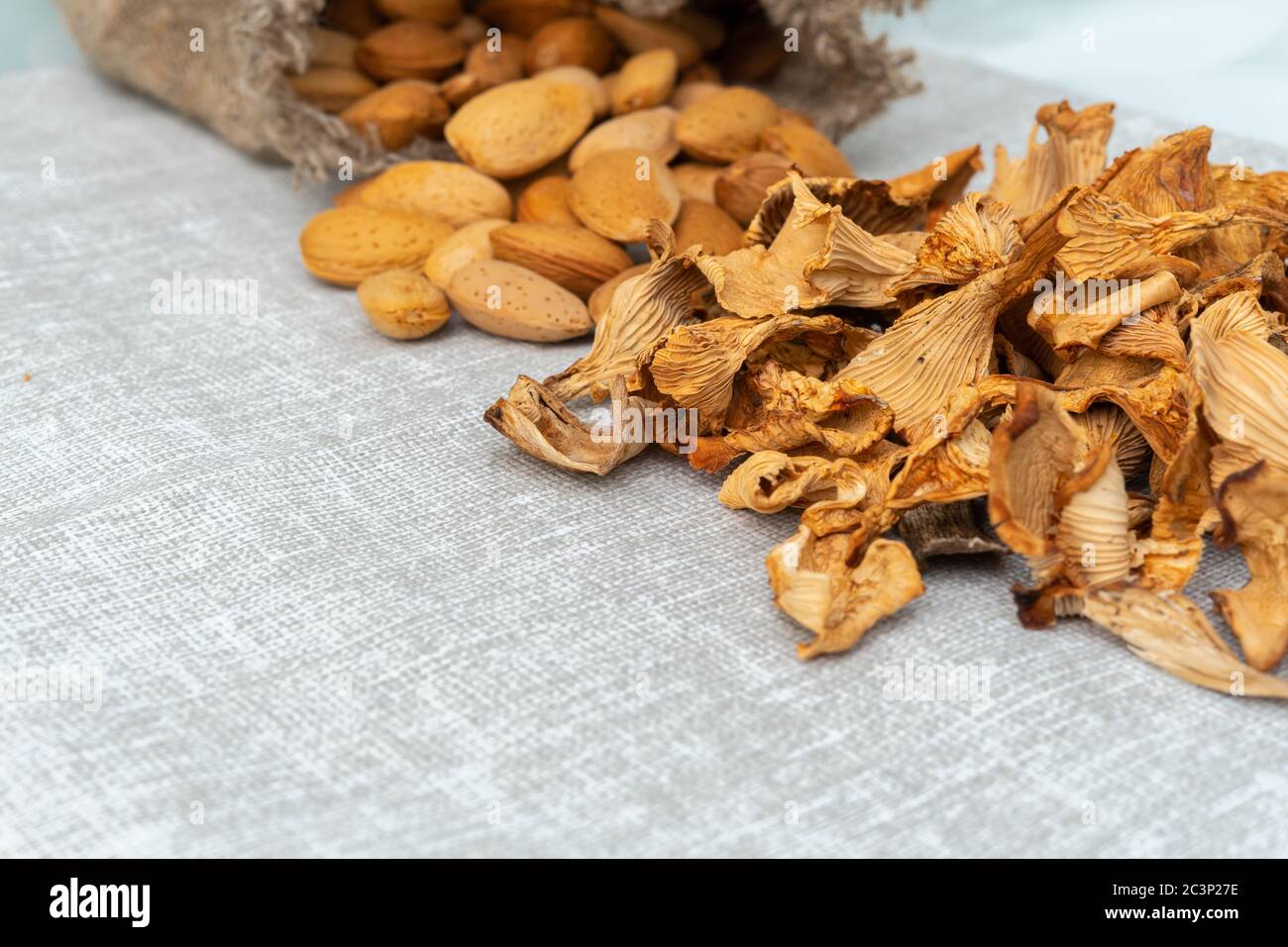 Trockene Pilze und Mandeln nicht geschält in der Zusammensetzung mit einem Leinenbeutel. Vegane Produkte Stockfoto