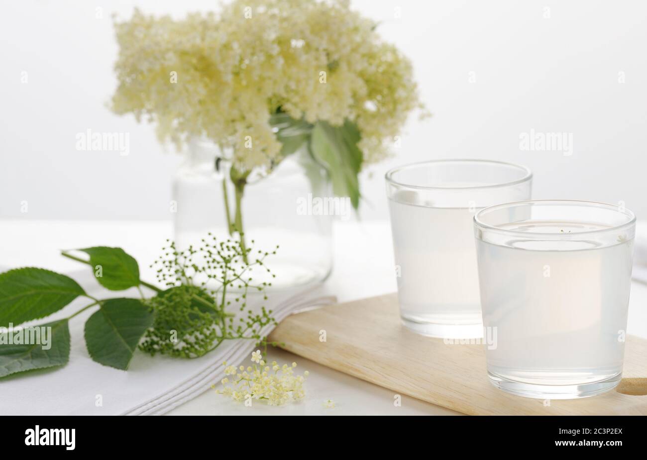Hausgemachte erfrischende Holunderblüten Limonade und Holunderblüten Cluster über weißem Hintergrund.Bild mit selektivem Fokus, horizontal. Stockfoto