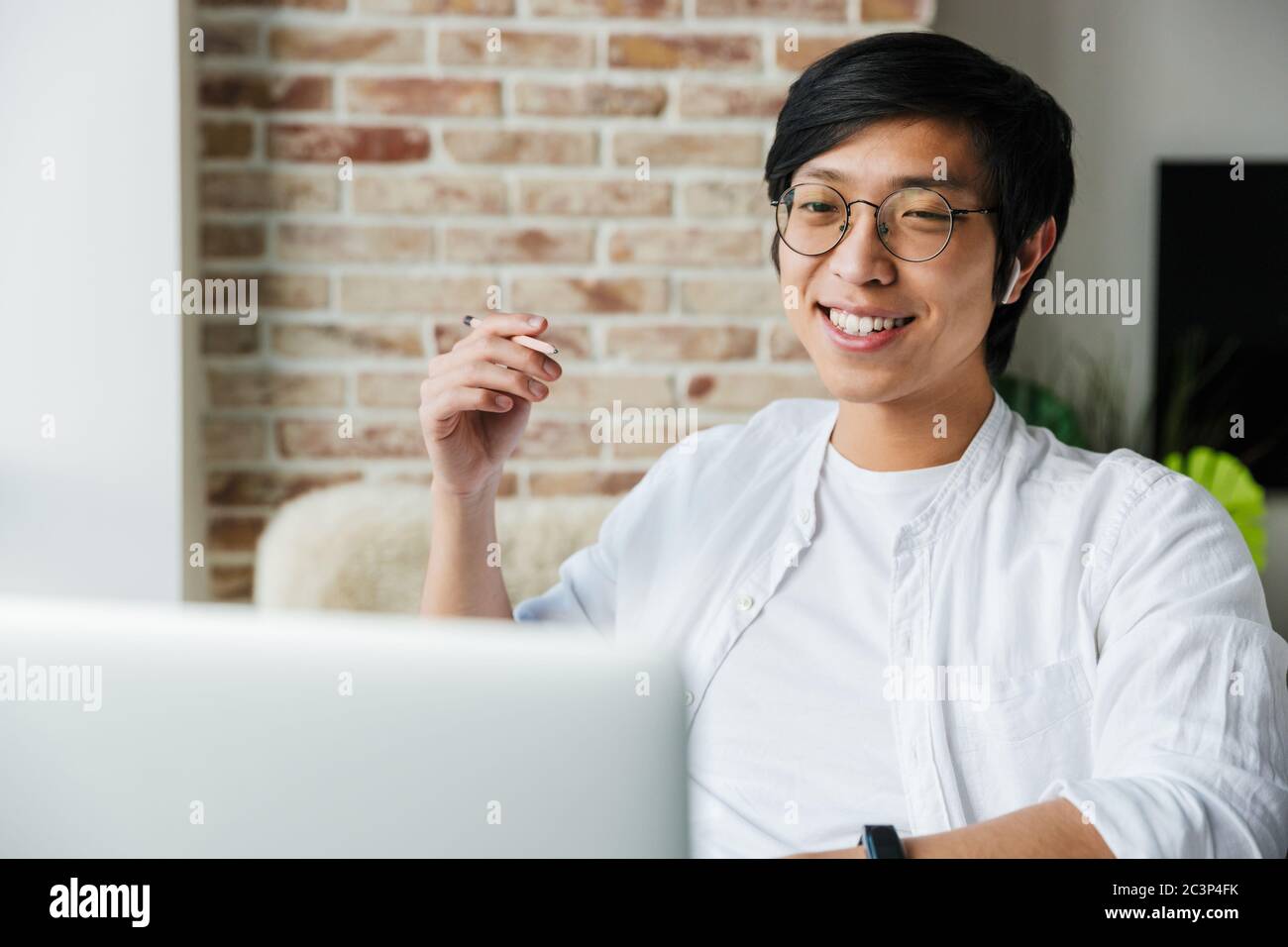 Bild von schönen jungen asiatischen Mann tragen Kopfhörer mit Laptop, während am Tisch im Büro sitzen Stockfoto
