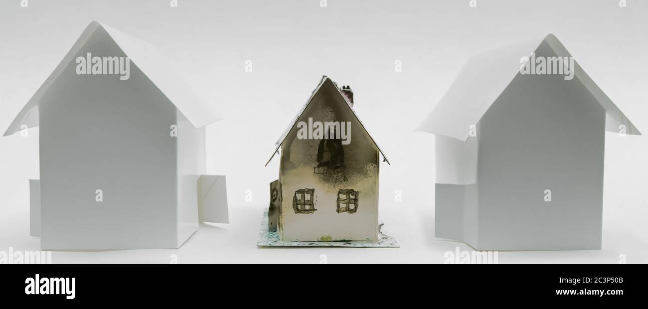Ein kleines altes, veraltetes Haus, zwischen zwei brandneuen, aber seelenlos. Modell aus Pappe.. Stockfoto