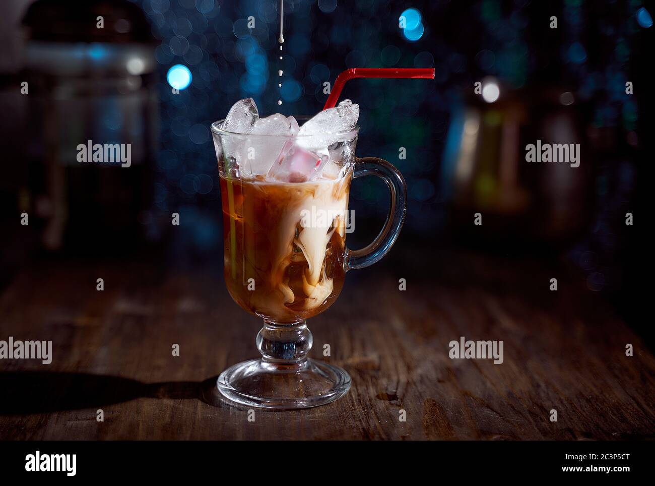 Kalter Kaffee mit Milch auf einem Holzbrett. Blauer unscharfer Hintergrund Stockfoto