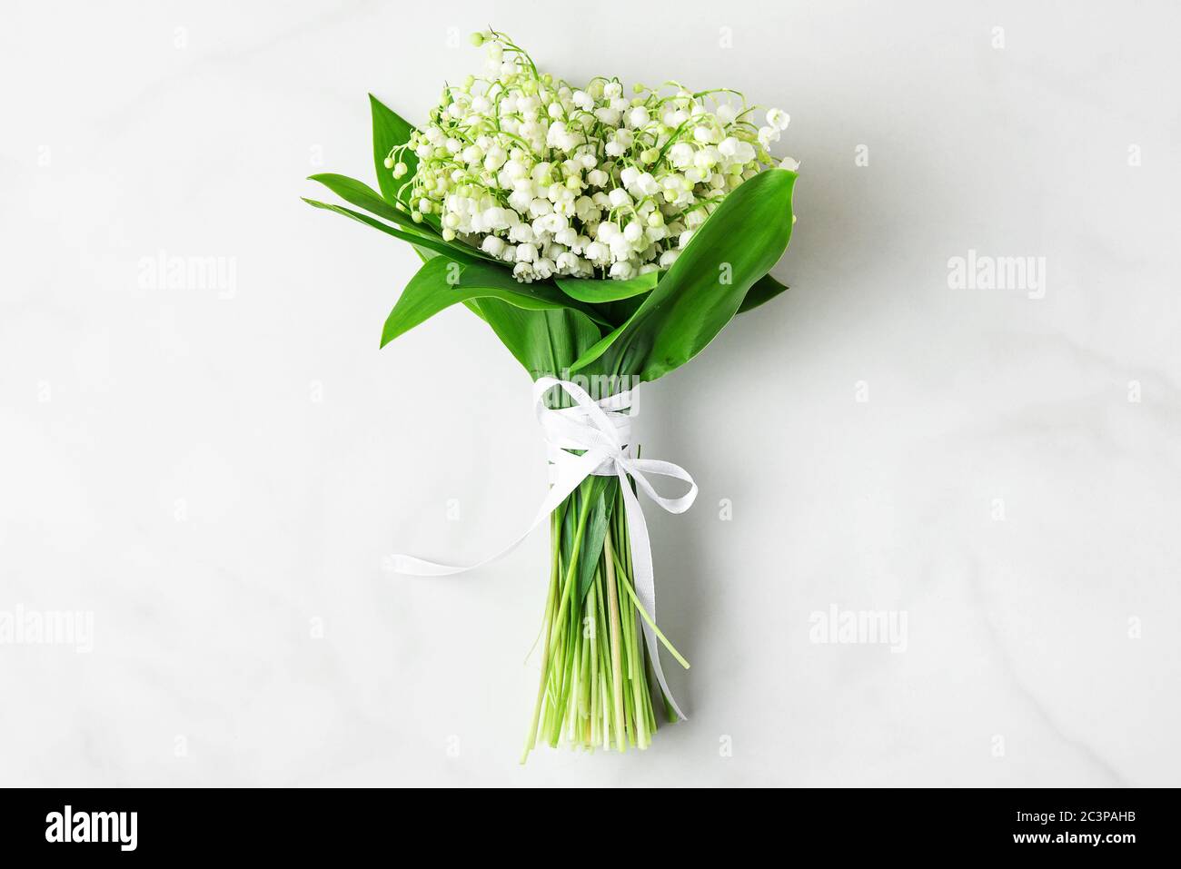 maiglöckchen Blumenstrauß auf weißem Marmorboden. Flache Lage. Draufsicht. Hochzeit oder Urlaub Hintergrund Stockfoto