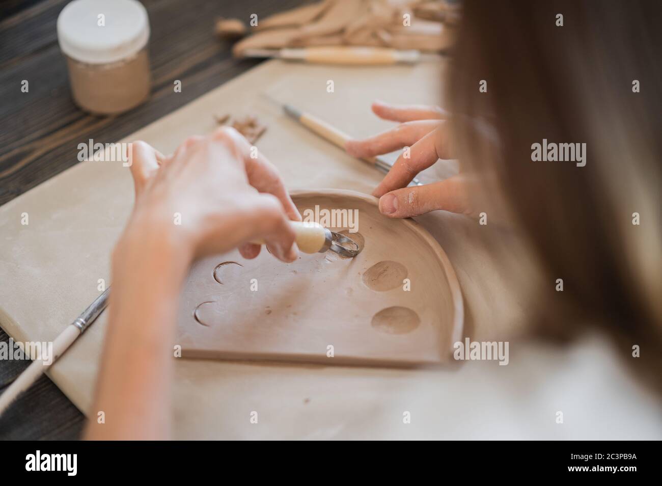 Nahaufnahme eines Töpfermeisters, Spezialwerkzeug zum Schneiden von Ton. Weibliche Künstlerin schneiden mit einem Holzschlaufe Werkzeug Stockfoto
