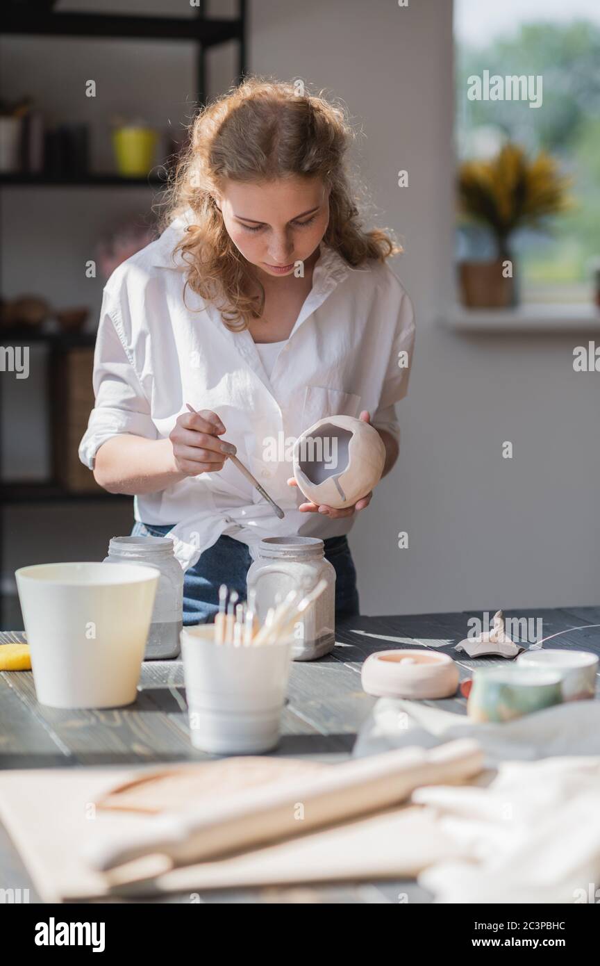 Produktionsprozess der Keramik. Anwendung der Glasurbürste auf Keramikgeschirr. Stockfoto