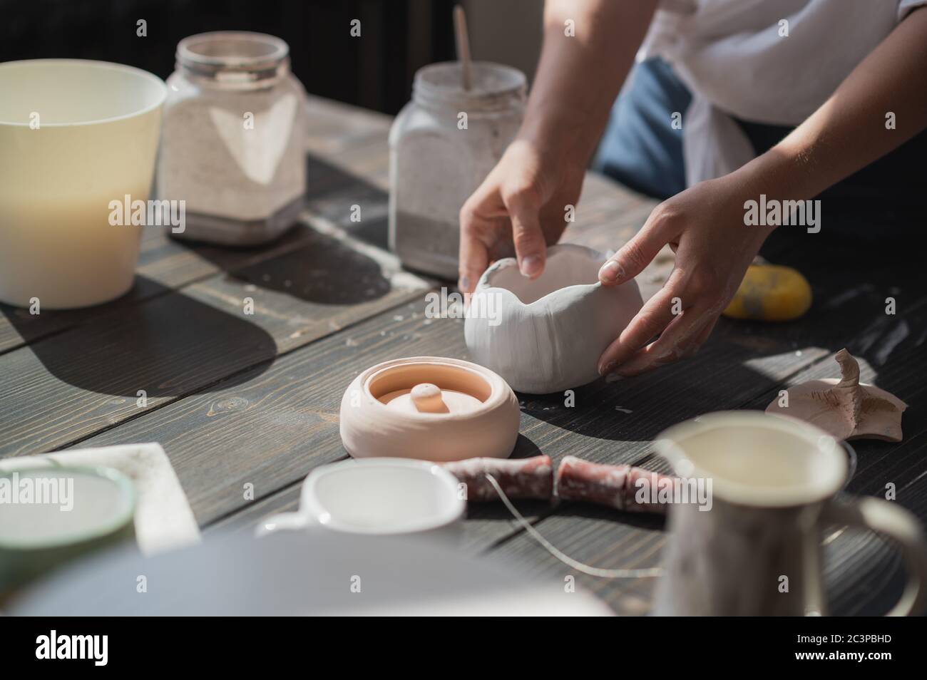 Produktionsprozess der Keramik. Anwendung der Glasurbürste auf Keramikgeschirr. Stockfoto
