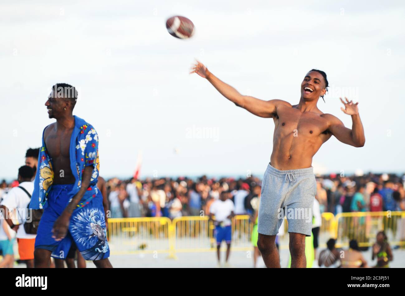 MIAMI - 15. MÄRZ 2019: Junge Männer passieren einen amerikanischen Fußball bei einem Treffen von Studenten feiern Frühlingsferien in South Beach. Stockfoto