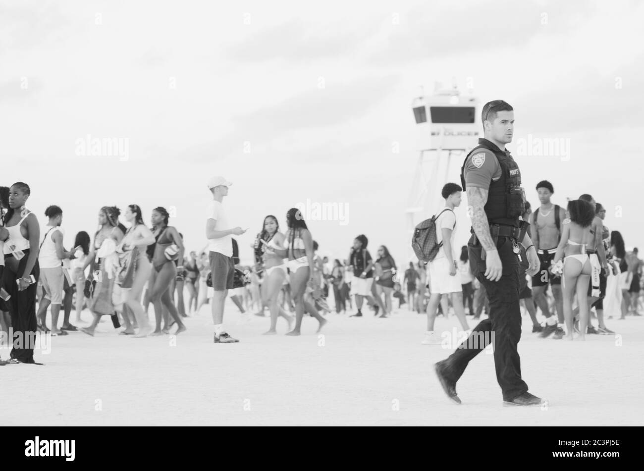 MIAMI - 15. MÄRZ 2019: Ein Polizist geht durch Massen von jungen Menschen, die sich in South Beach für die jährlichen Frühlingsferien von der Schule versammeln. Stockfoto