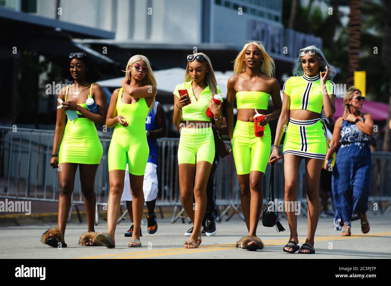 MIAMI - 17. MÄRZ 2019: Eine Gruppe junger Frauen in knallbunten, passenden neongrünen Outfits geht in den Frühlingsferien auf dem Ocean Drive in South Beach spazieren. Stockfoto