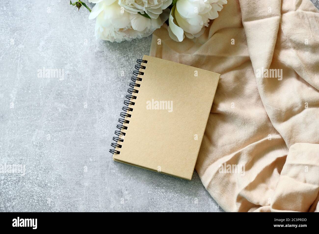 Kraftpapier Notizbuch oder Hochzeitsfotoalbum mit Pfingstrosen auf Beton Stein Tisch. Flach liegend, Draufsicht. Stockfoto