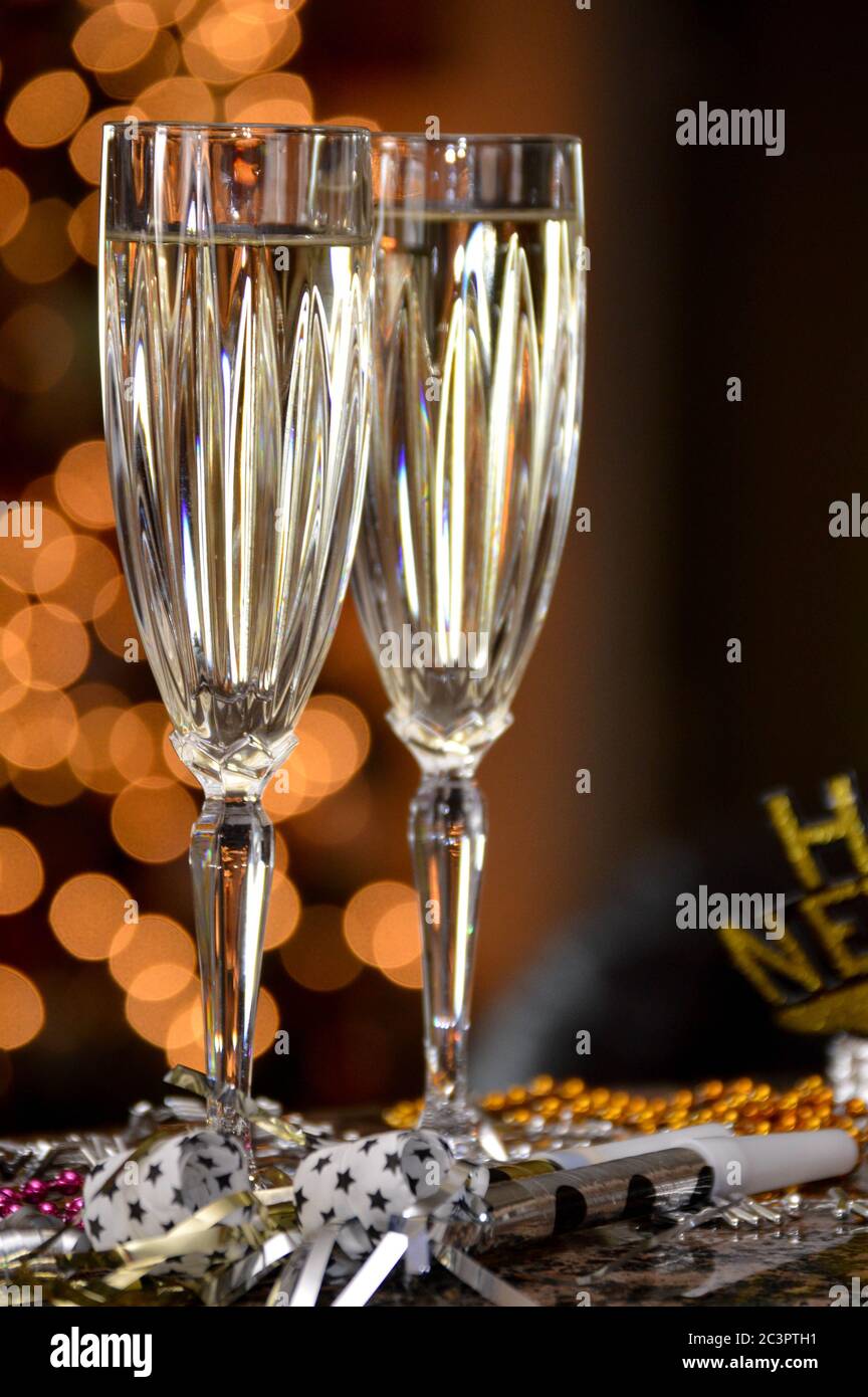 Silvesterfeier für zwei Personen mit Sektflöten und Weihnachtsbeleuchtung im Hintergrund Stockfoto