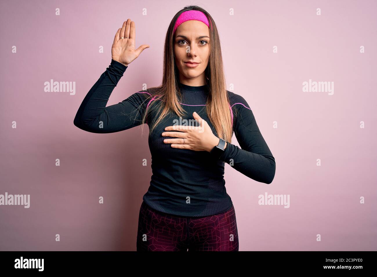 Junge blonde Fitness-Frau trägt Sport-Workout-Kleidung über isolierten Hintergrund Fluchen mit Hand auf der Brust und offene Handfläche, was ein Loyalität Versprechen Stockfoto