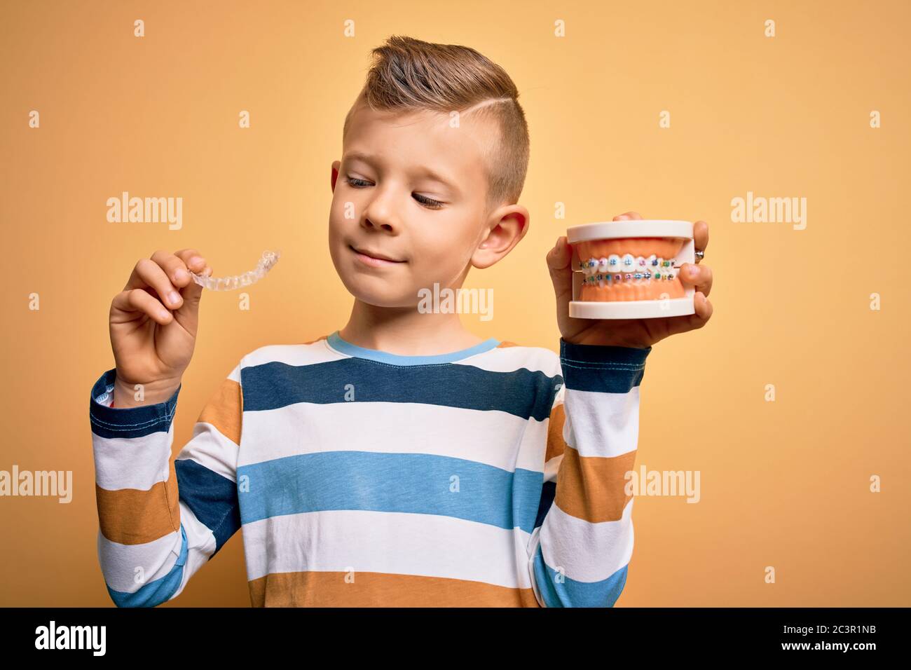 Kleiner Junge mit professioneller kieferorthopädischer Zahnbürste mit Metallspangen und abnehmbarem, unsichtbaren Ausrichter. Komparation von zwei Zahnglättungsbehandlungen Stockfoto