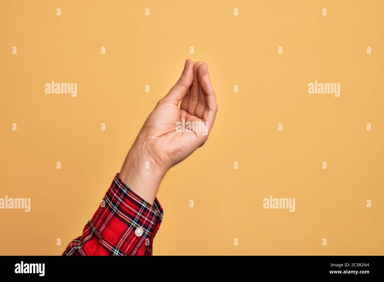 Hand des kaukasischen jungen Mannes, der Finger über isolierten gelben Hintergrund tut italienische Geste mit Fingern zusammen, Kommunikation Geste movemen Stockfoto