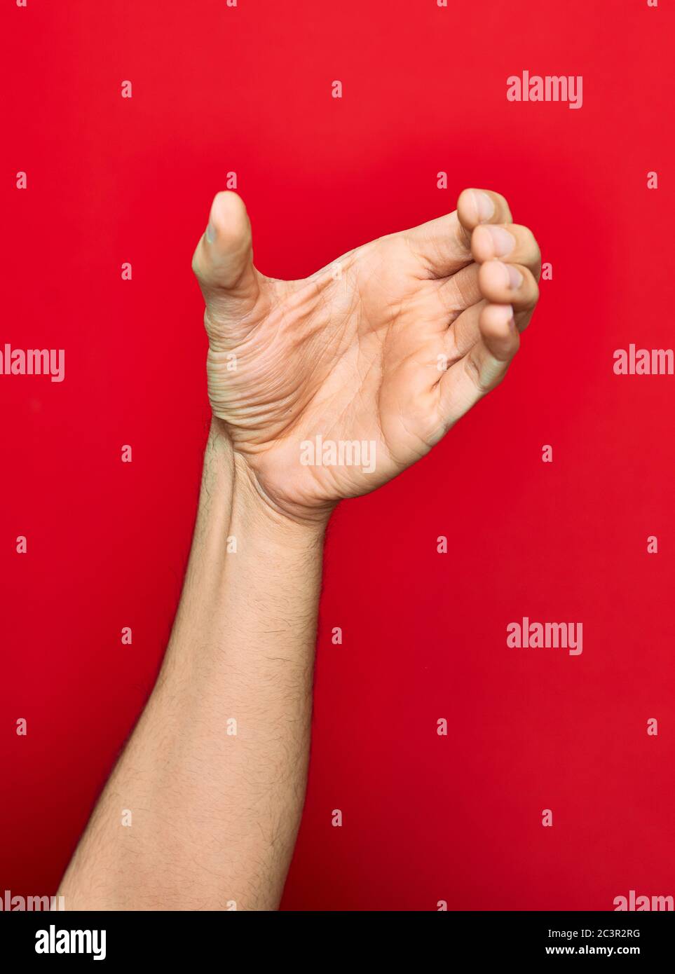 Schöne Hand des Mannes zeigt Finger angehoben tun halten Geste über isolierten roten Hintergrund Stockfoto