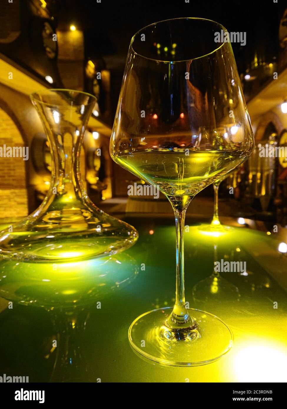 Diffuse Lichter und Ornamente bilden den Hintergrund für eine Nahaufnahme eines Glases Weißwein Stockfoto