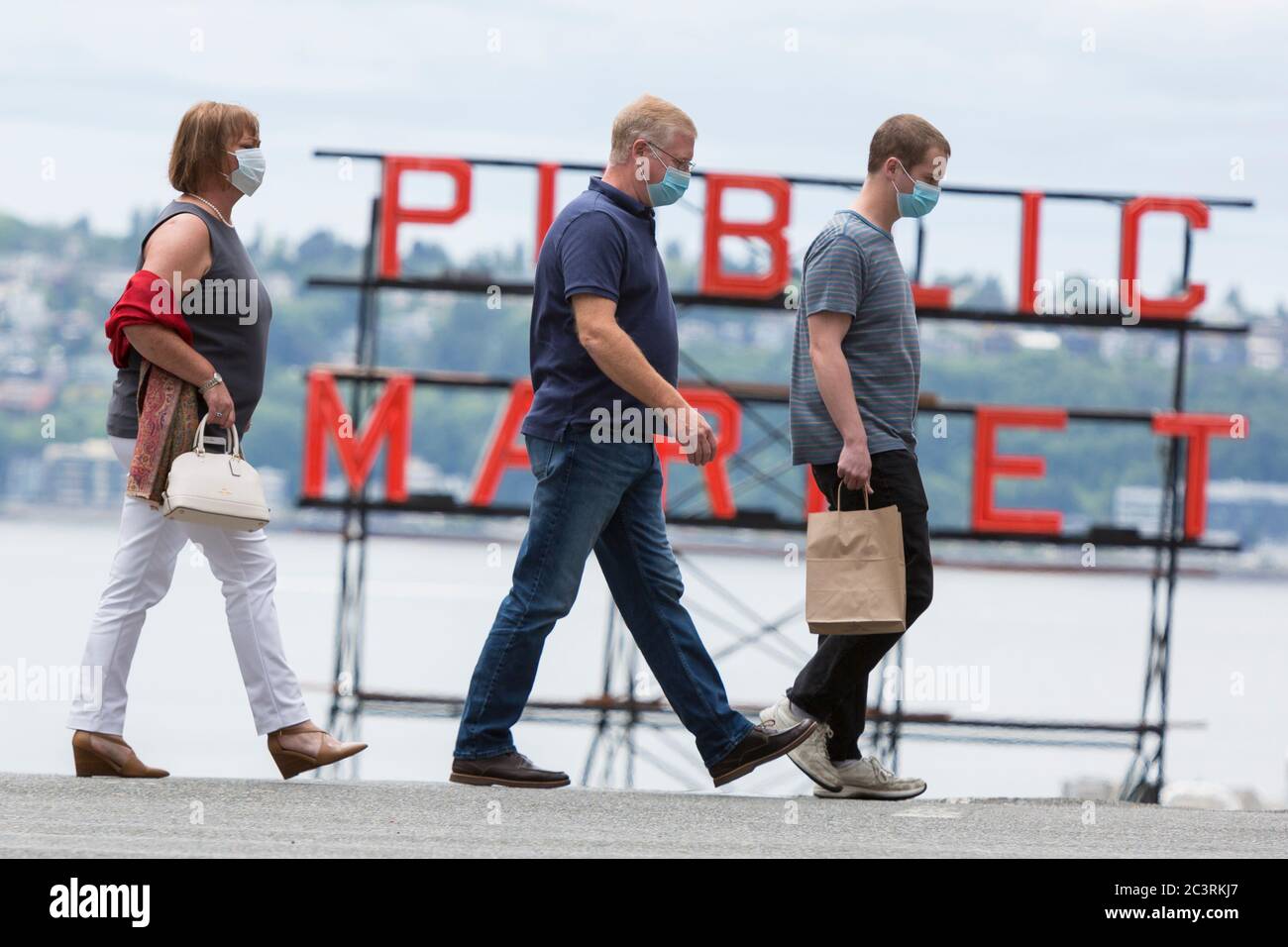 Besucher mit Gesichtsmasken überqueren die Pine Street in der Nähe des Pike Place Market in Seattle, da die Einschränkungen für die Coronavirus-Pandemie am Sonntag, den 21. Juni 2020 gelockert werden. King County zog am Freitag in Phase 2 um, als Teil des Safe Start-Wiedereröffnungsplans von Gouverneur Jay Inslee, um die Kapazität der Einzelhandelsgeschäfte auf 30 % der maximalen Gebäudeauslastung zu erhöhen. Stockfoto