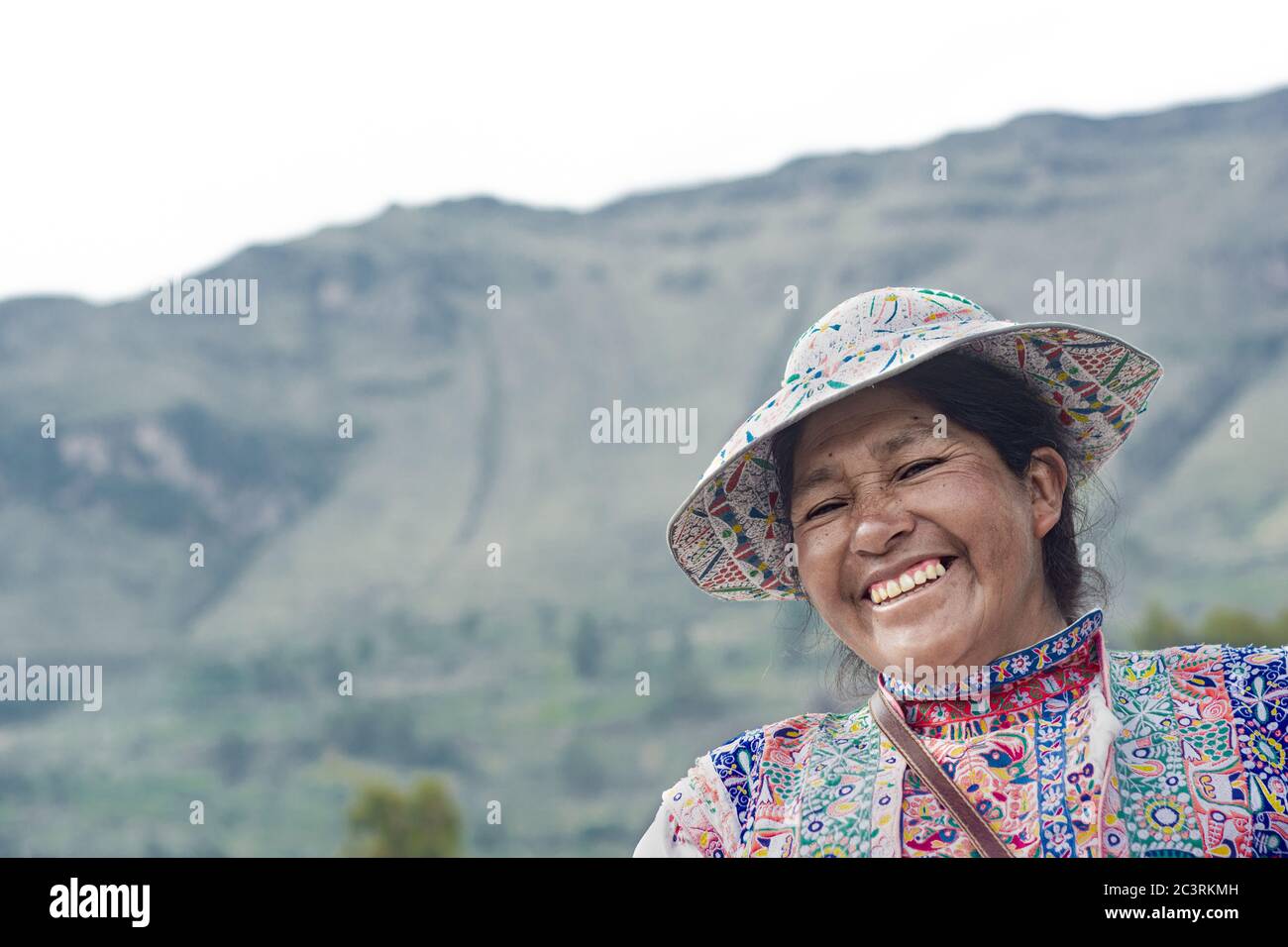 YANQUE, COLCA VALLEY, PERU - 20. JANUAR 2018: Portrait einer nicht identifizierten peruanischen Mutter mit tradicional Kleidung lachend in der traditionellen Co Stockfoto