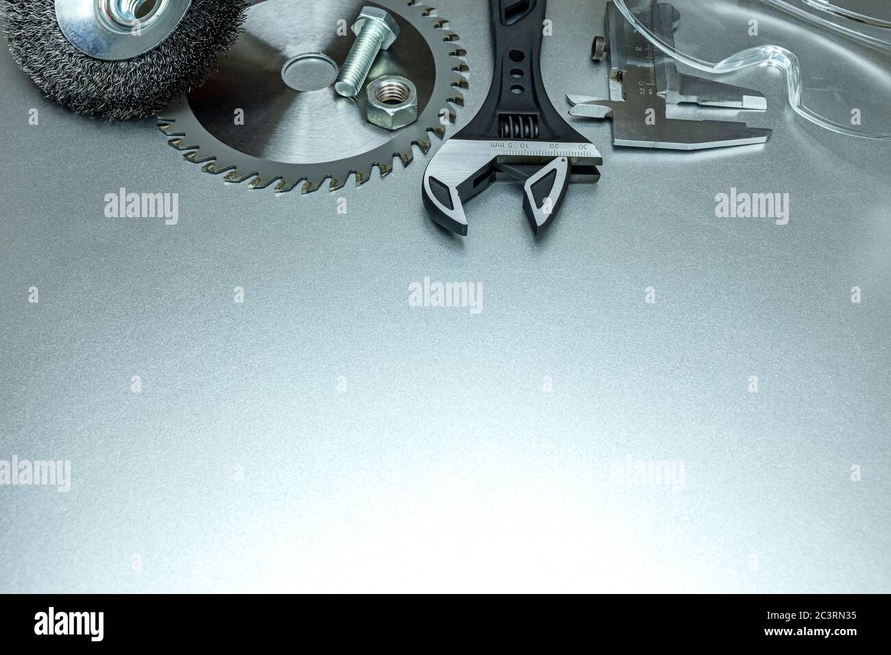 Moderne Werkzeuge zum Schneiden und Schleifen, inklusive Schutzbrille. Flach auf grauer Metalloberfläche legen Stockfoto