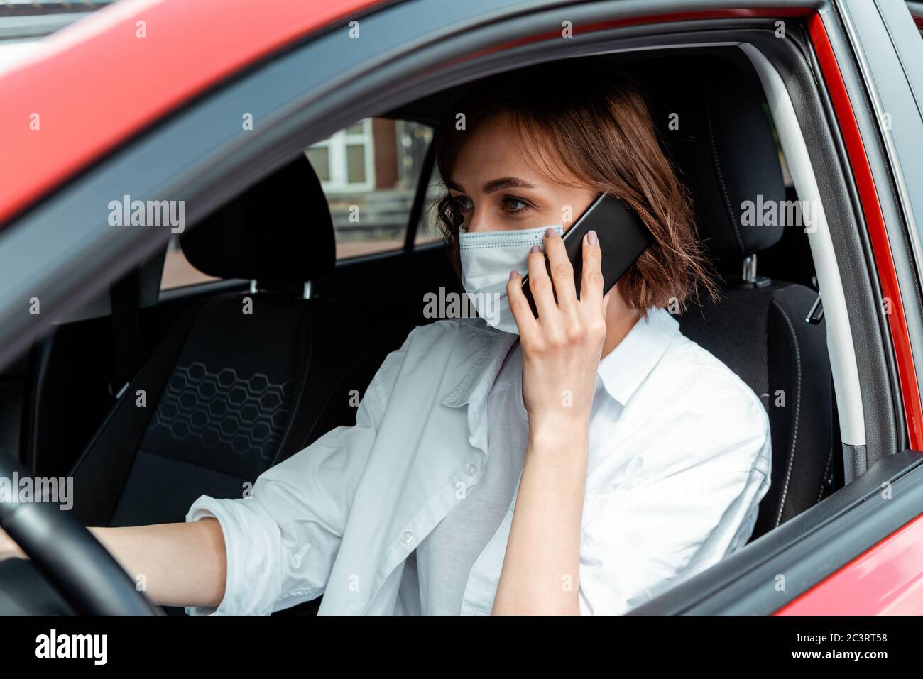 Frau in medizinischer Maske, die während der covid-19 Pandemie am Handy spricht Stockfoto