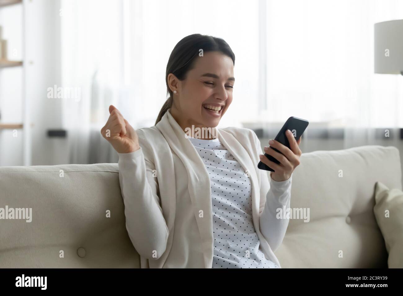 Frau, die auf Handy-Bildschirm bekam fantastische Angebot fühlt sich glücklich Stockfoto