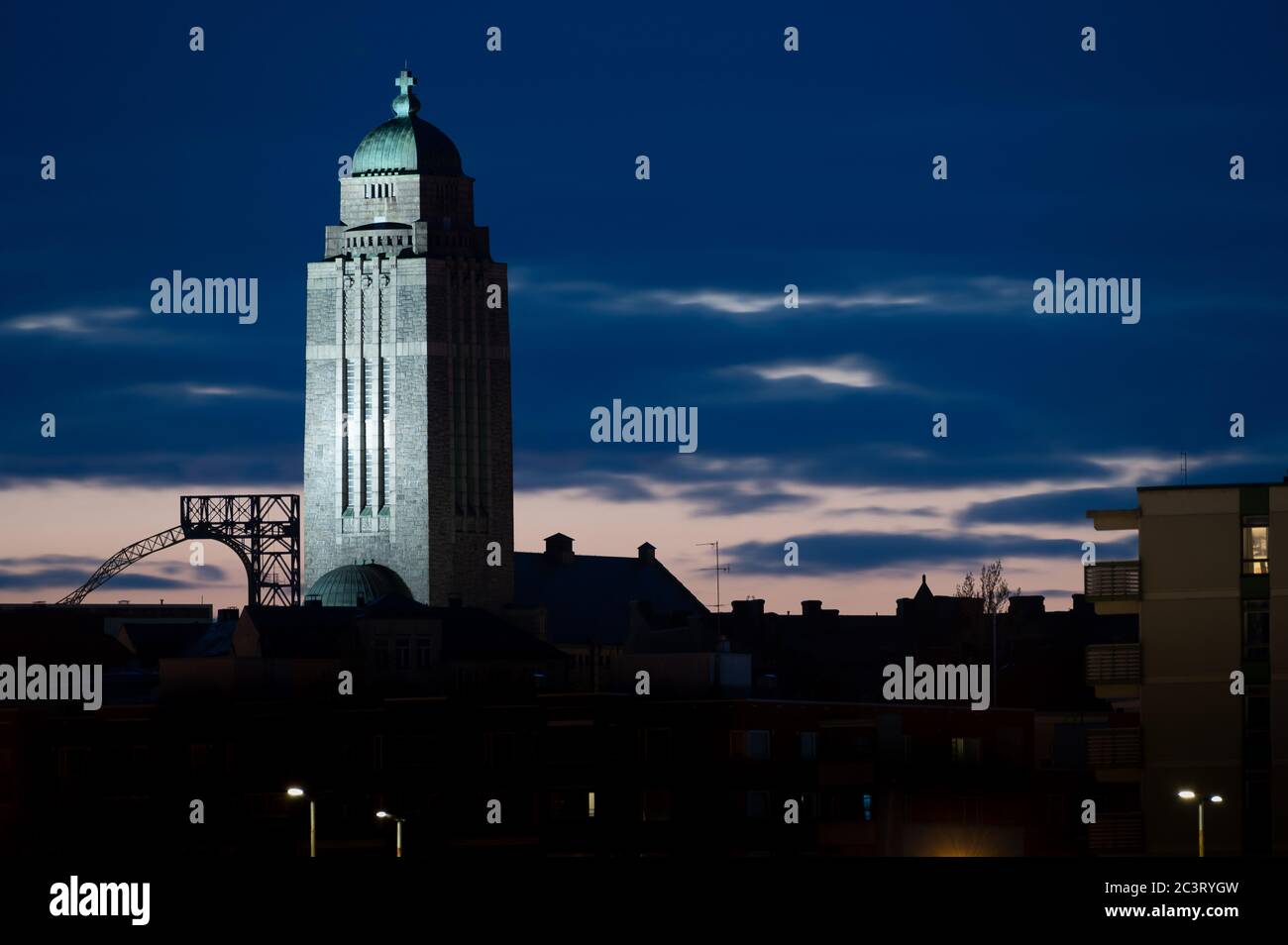 Eine Silhouette eines Wohnviertels von Kallio in der Nacht mit beleuchteten Kirchturm gegen Wolken. Stockfoto