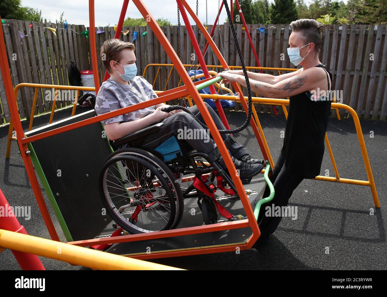 Gregor Marshall mit seiner Mutter Karen als Gregor fährt im Freigelände des Craighalbert Centers mit der Rollstuhlschaukel. Coronavirus-Anpassungen wurden im Scottish Centre for Children with Motor Impairments, Craighalbert Centre, Cumbernauld, installiert, da Schottland die Maßnahmen zur Sperrung des Coronavirus schrittweise aufhebt. Stockfoto