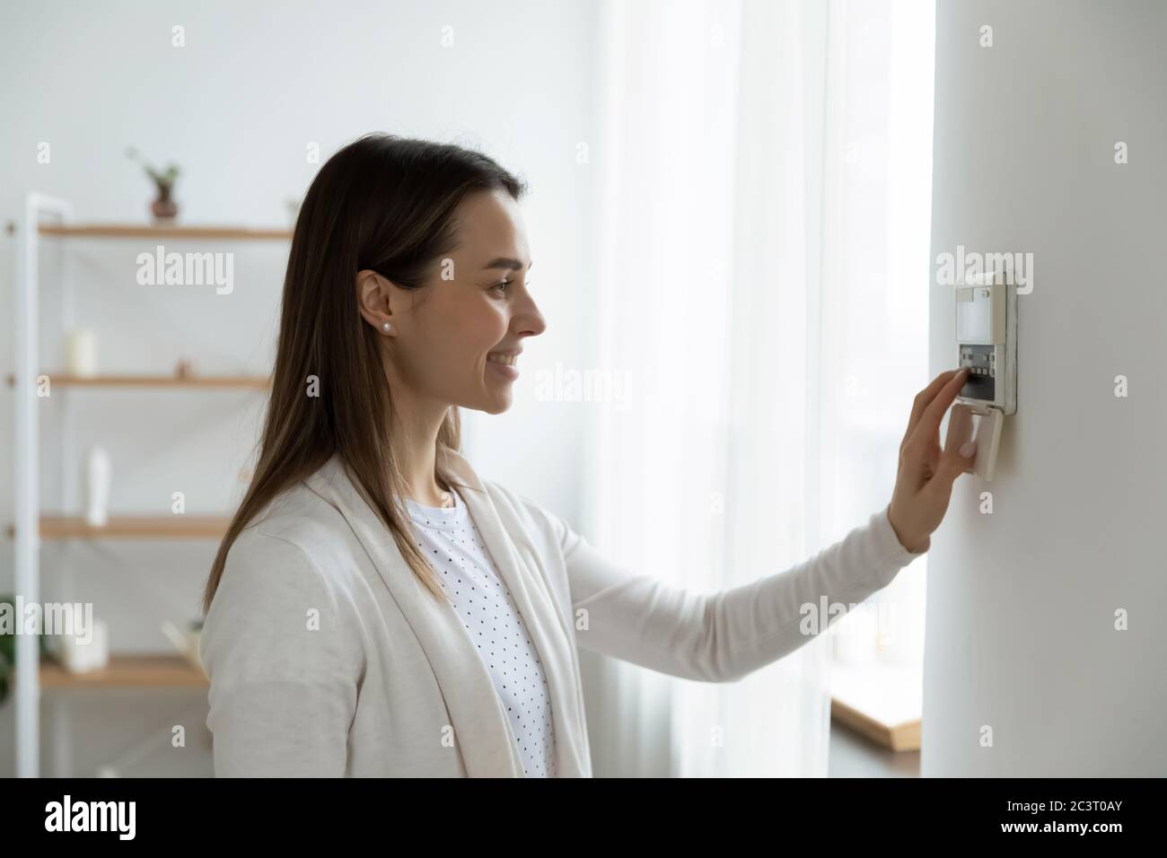 Lächelnde Frau Einstellung Grad bequeme Temperatur mit Thermostat Stockfoto