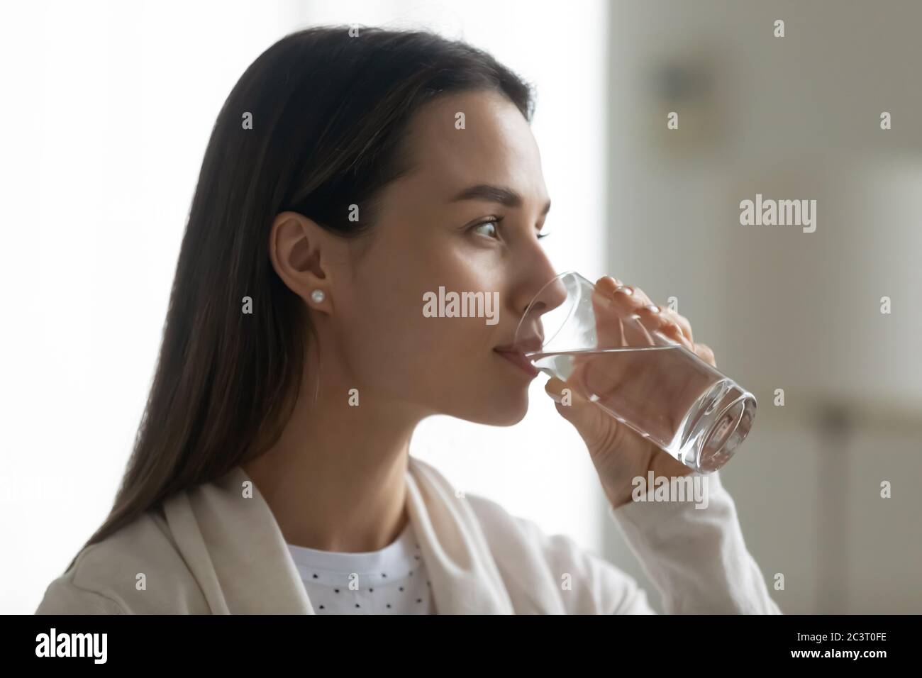 Schöne Frau hält Glas Trinkwasser Blick in der Ferne Stockfoto