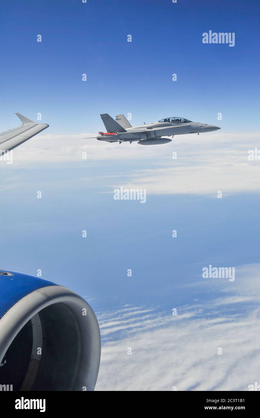 Ein Blick von innen Passagier-Jetliner-Kabine eines militärischen Jet-Kämpfer eskortiert kommerzielle Flugzeuge in großer Höhe. Stockfoto