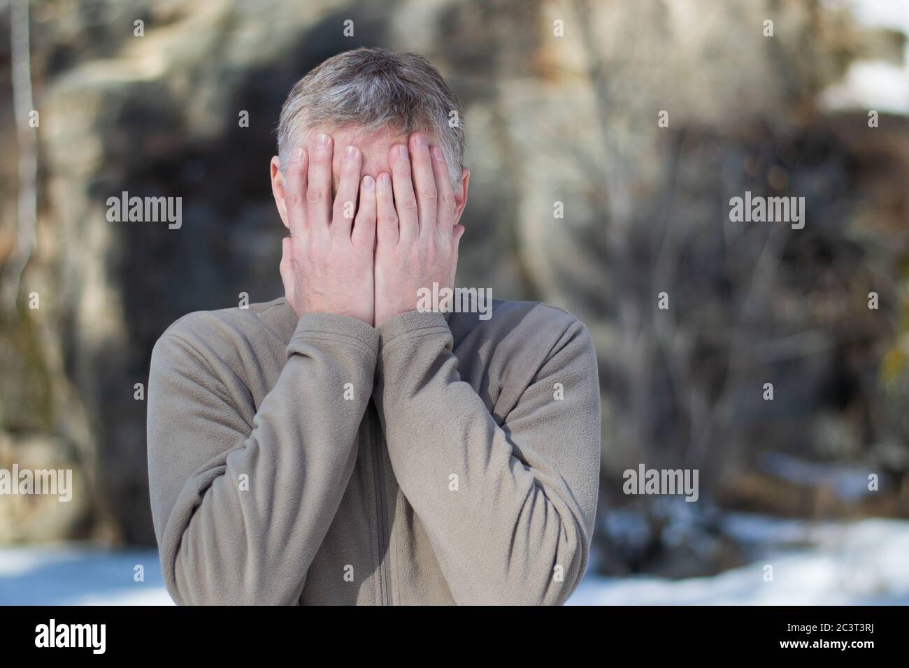 Porträt eines Mannes mittleren Alters auf der Straße, das Gesicht mit den Händen bedeckt. Ausdruck von Traurigkeit, Zweifel, Verzweiflung. Krisenkonzept. Stockfoto