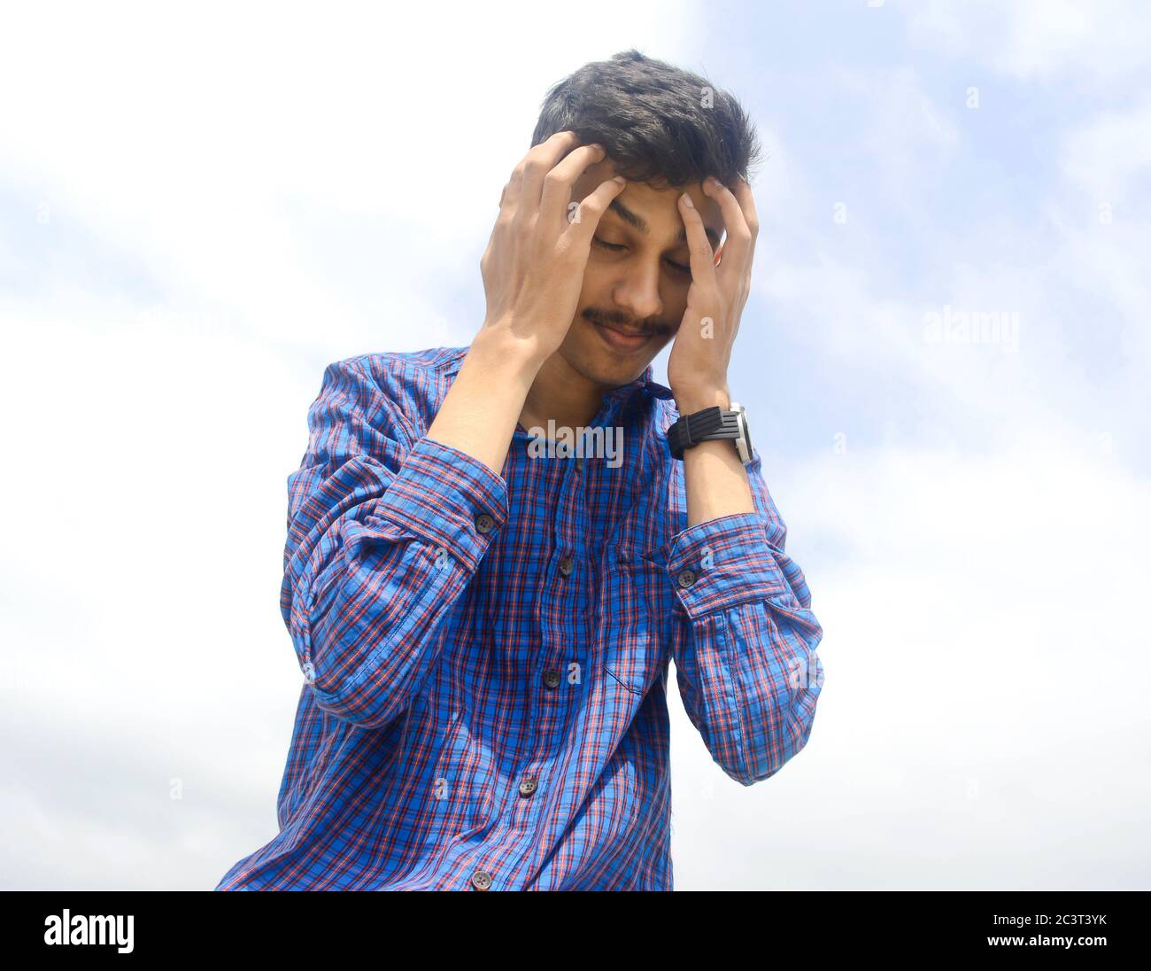 Junger Mann, der unter starken Kopfschmerzen oder Migrant.Sky Hintergrund leidet. Stockfoto
