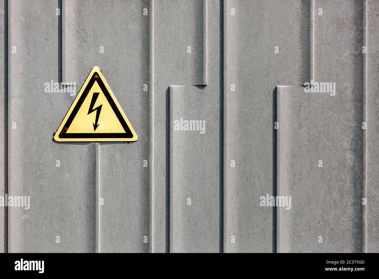 Zeichen der Hochspannung auf einer grauen Metalloberfläche. Symbol für elektrische Gefahr auf einem Warnschild auf grauem Hintergrund Stockfoto